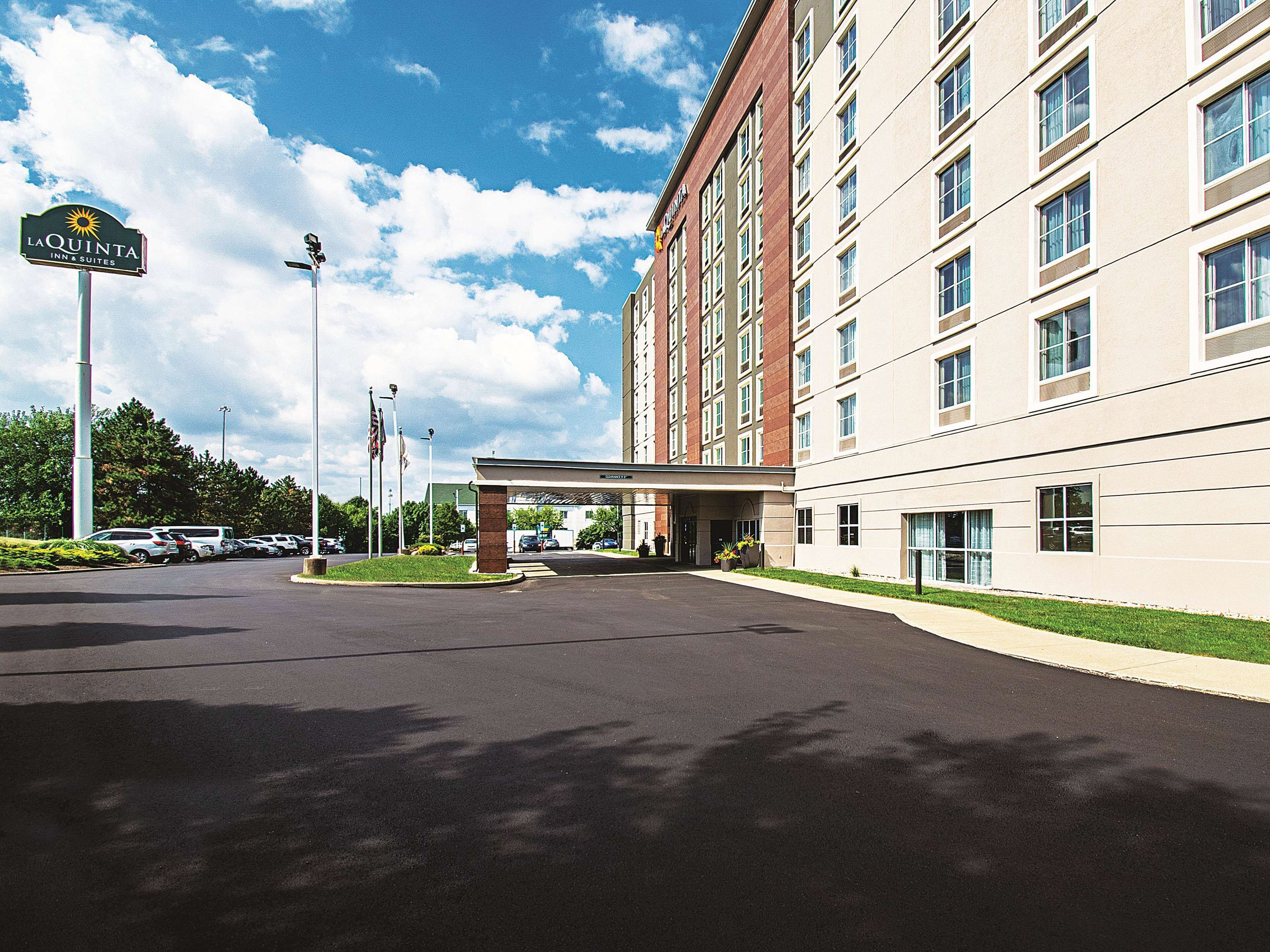 A hotel entrance with a covered walkway, a parking lot, and a clear sky.
