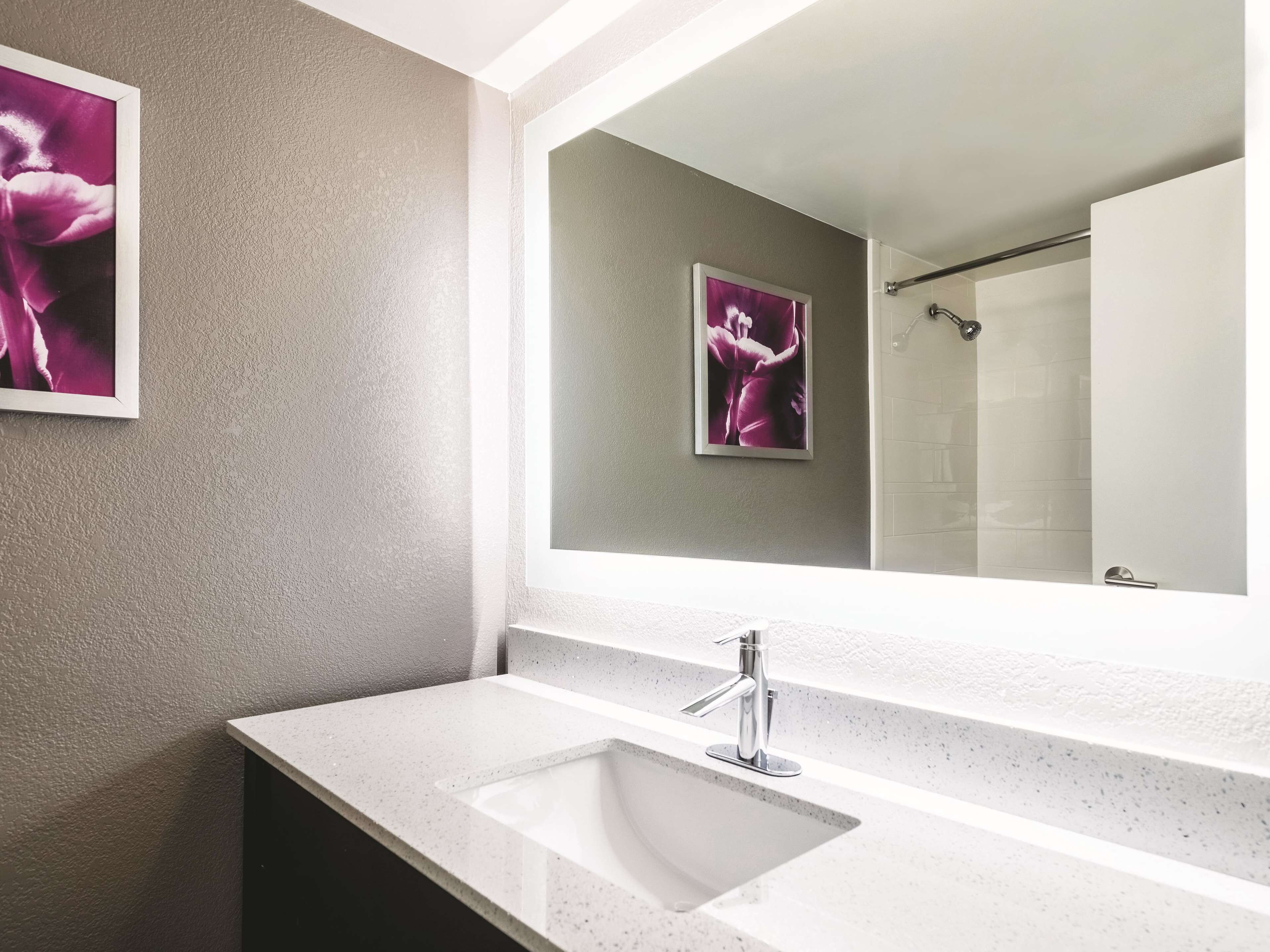 Une salle de bain moderne avec un grand miroir, un lavabo blanc et un espace douche.