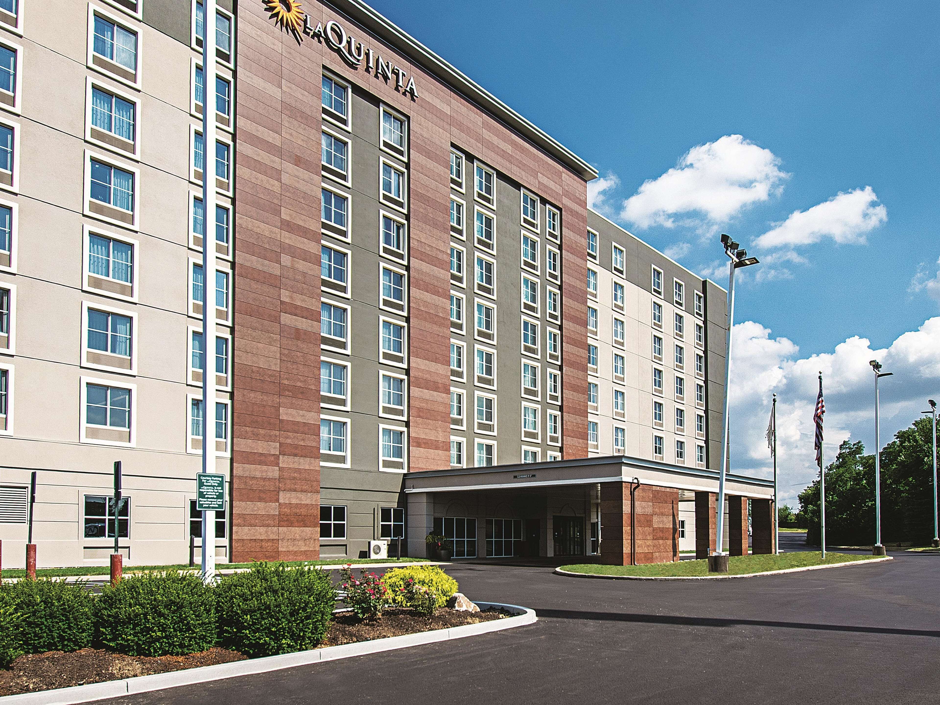 A multi-story hotel with a prominent entrance, a covered parking area, and a landscaped garden.