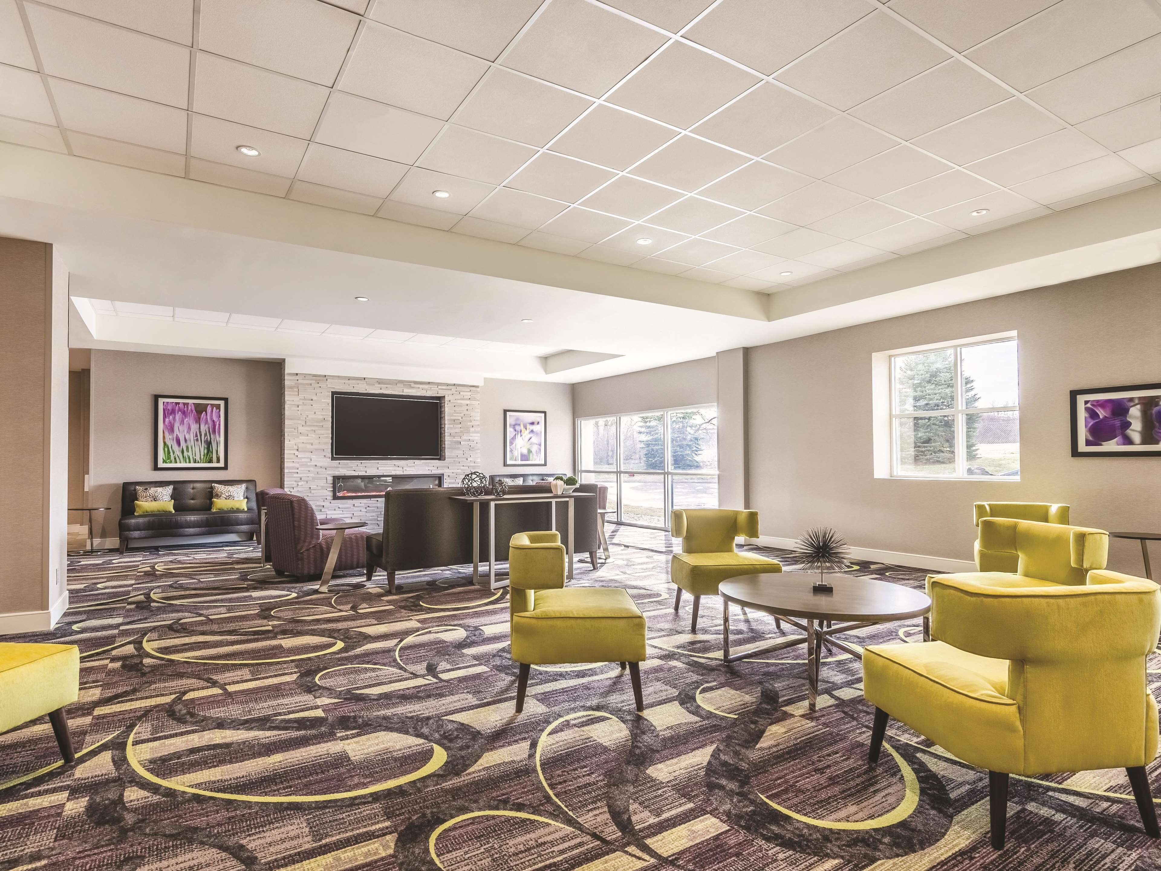 A hotel lobby with a seating area, a fireplace, and a large window.