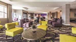 A spacious lobby with modern seating, a central coffee table, and a cityscape mural on the wall.