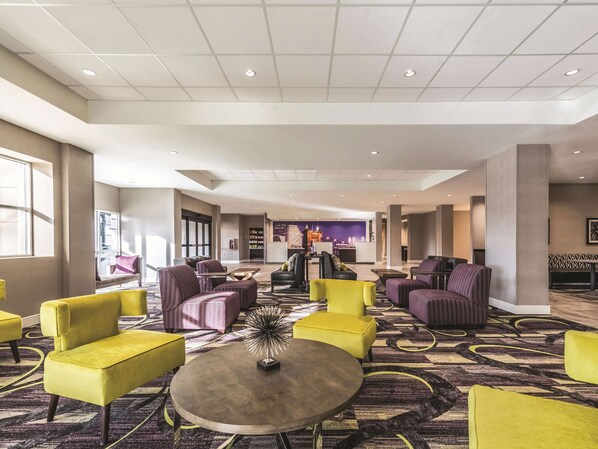 A spacious lobby with modern seating, a central coffee table, and a cityscape mural on the wall.