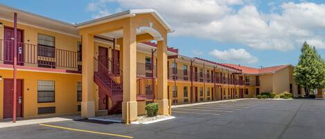 A motel with a central entrance, multiple balconies, and a parking lot.
