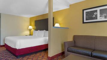Una habitación de hotel con cama, sofá, mesa y lámpara.