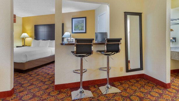 A hotel room with a bed, two bar stools, a mirror, and a carpeted floor. - Best Western Benton Inn (Benton)