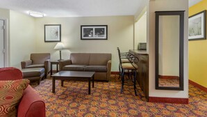 A hotel room with a sofa, armchairs, a small table, a lamp, and a patterned carpet. - Best Western Benton Inn (Benton)