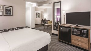A hotel room with a bed, a TV, a microwave, and a desk with a chair. - La Quinta Inn & Suites by Wyndham Columbia / Fort Meade (Jessup)
