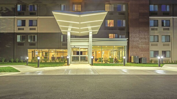 A hotel with a prominent sun logo, multiple floors, and a covered entrance area. - La Quinta Inn & Suites by Wyndham Columbia / Fort Meade (Jessup)