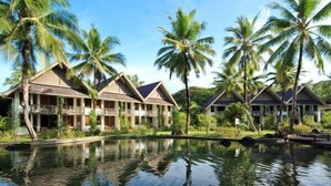 A resort with multiple bungalow-style buildings, a reflecting pool, and palm trees. - Palau Pacific Resort (Meyungs)