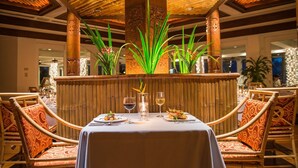 A restaurant with a central bar, wooden pillars, and a ceiling with bamboo elements. - Palau Pacific Resort (Meyungs)