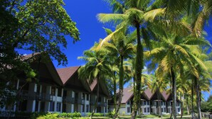 A resort with multiple-story buildings, palm trees, and a well-maintained lawn. - Palau Pacific Resort (Meyungs)