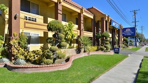 Un hotel de fachada amarilla, con varios balcones y un jardín bien cuidado.