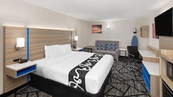 Una habitación de hotel con una cama grande, un escritorio, una silla, un televisor y una mesita.