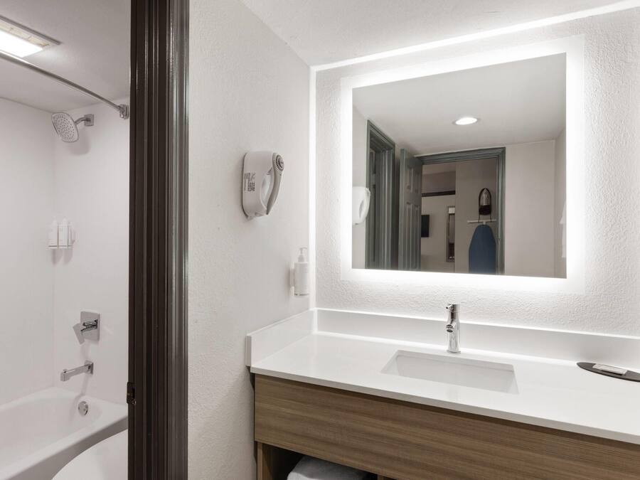 A modern bathroom with a white sink, a mirror, and a shower.