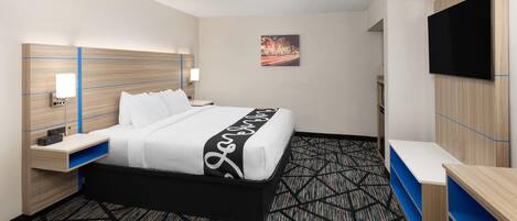 A hotel room with a bed, bedside tables, a TV, and a painting on the wall.