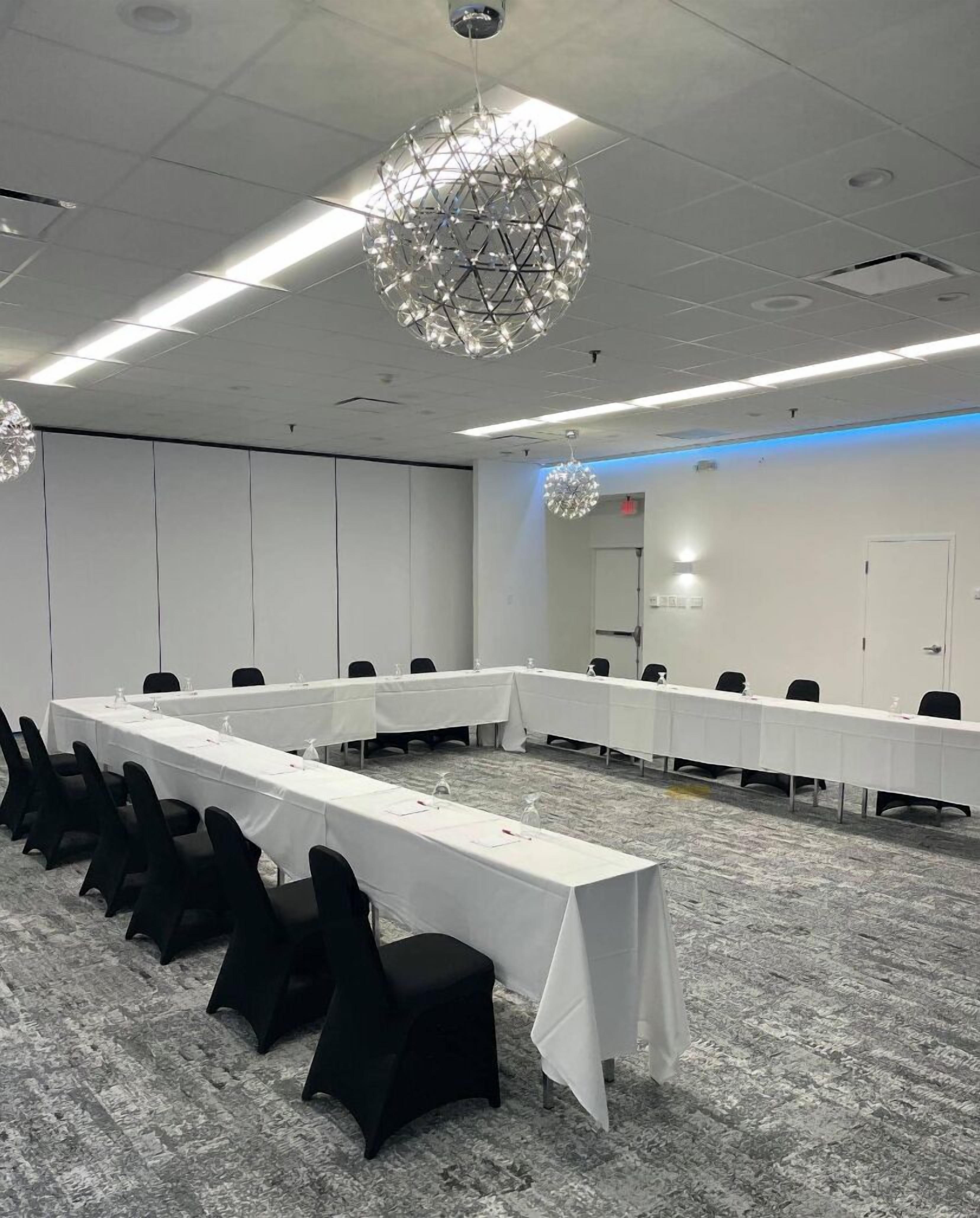 A conference room with a long table, black chairs, and a unique spherical chandelier.