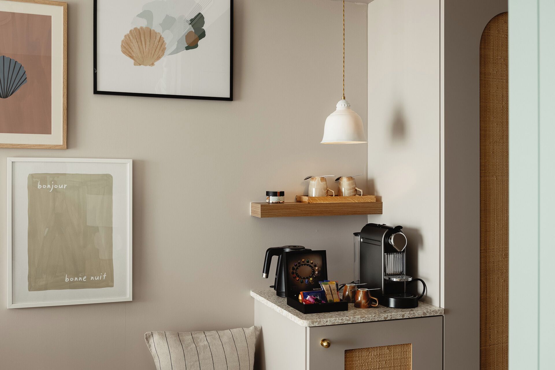 A kitchenette with a coffee maker, kettle, and tea pot on the counter.