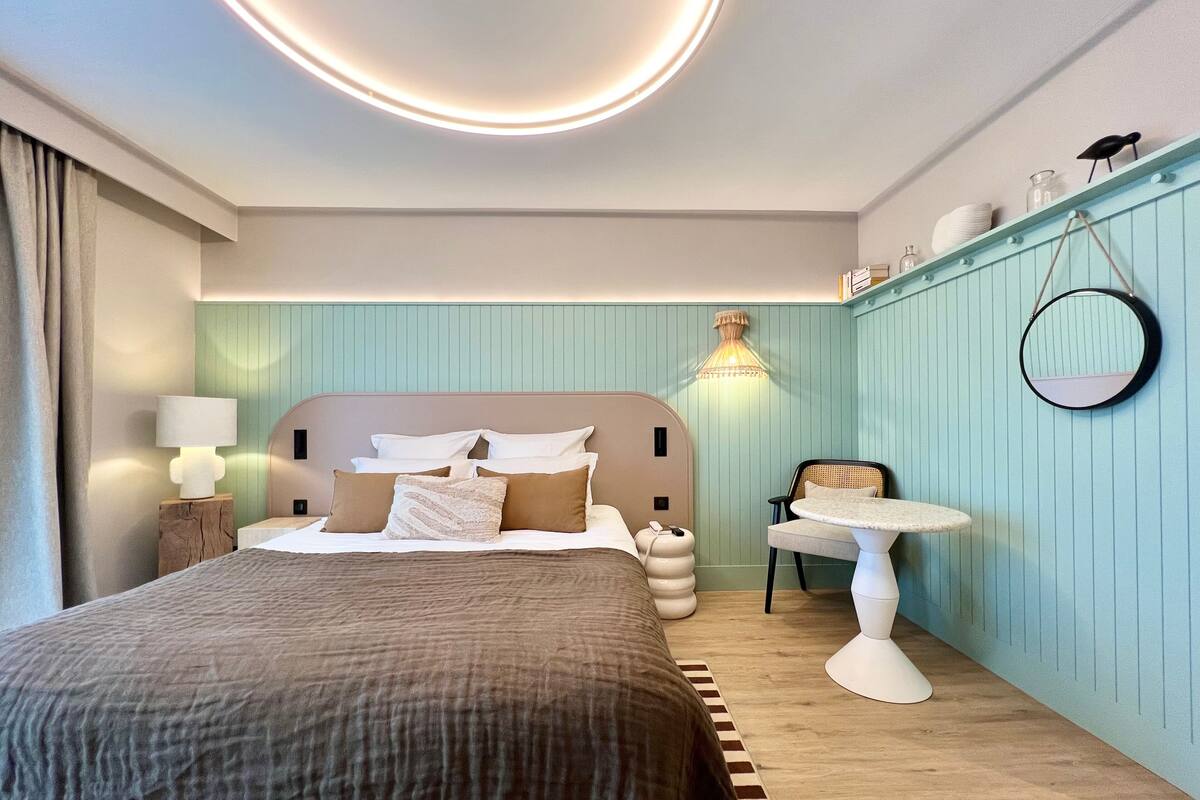 Une chambre à coucher moderne avec un grand lit, une table de chevet, une chaise et une petite table.
