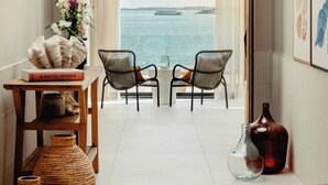 Une chambre moderne avec vue sur la mer, comprenant un canapé, une table avec des livres et des vases décoratifs.