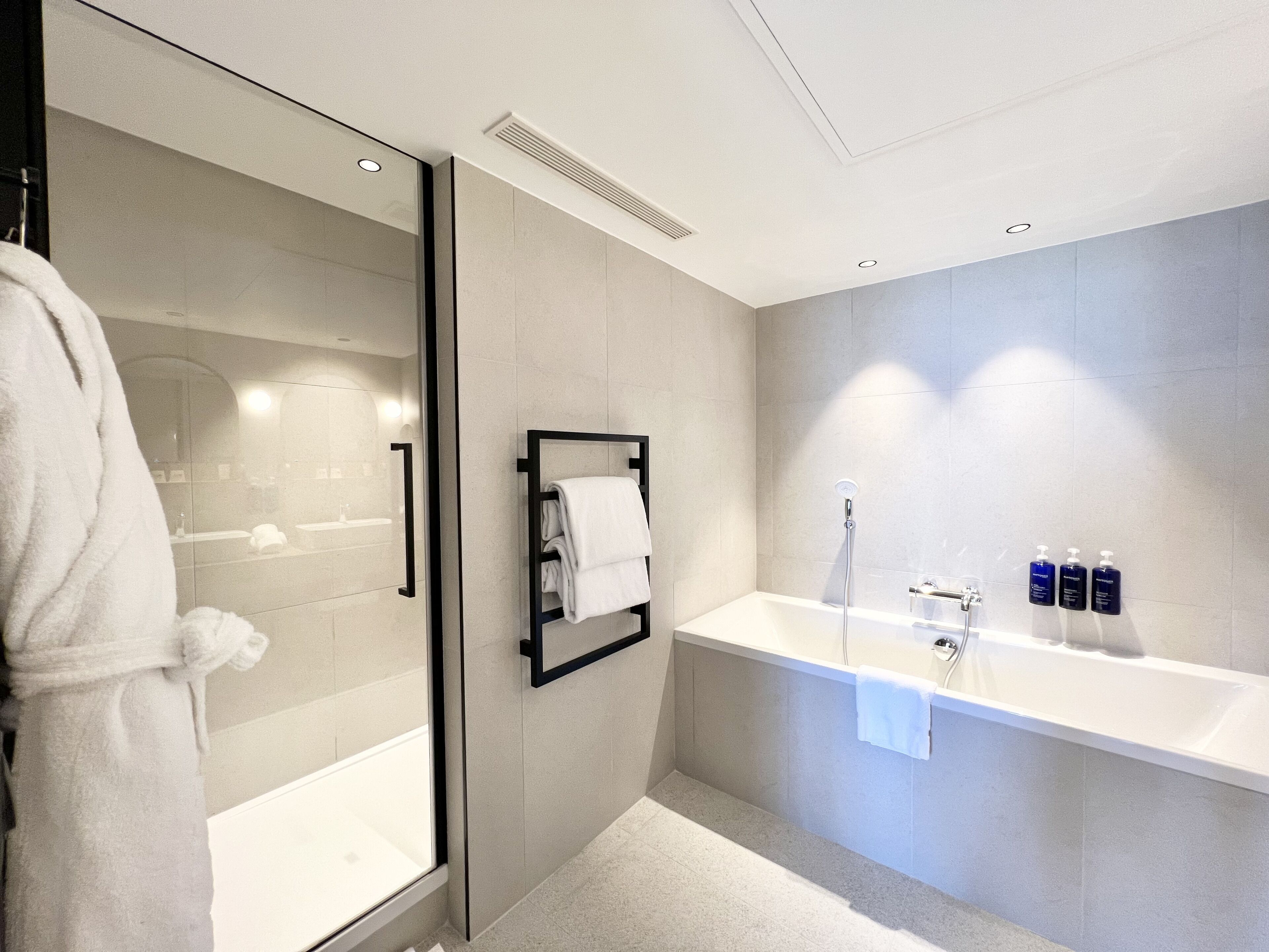 Un baño moderno con ducha de vidrio, bañera blanca y un espejo grande.