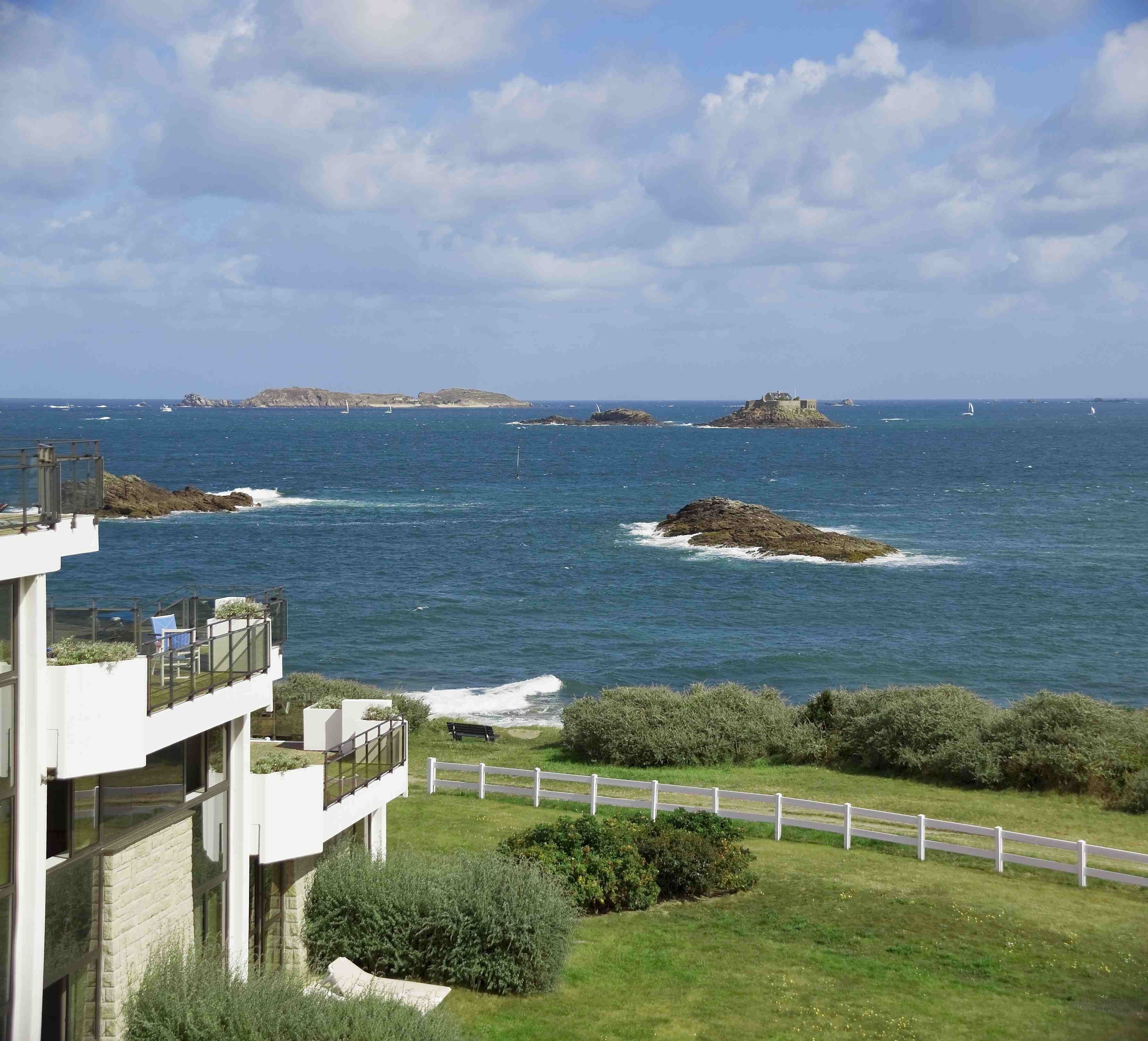 Une vue côtière avec un bâtiment moderne, des affleurements rocheux et la mer.