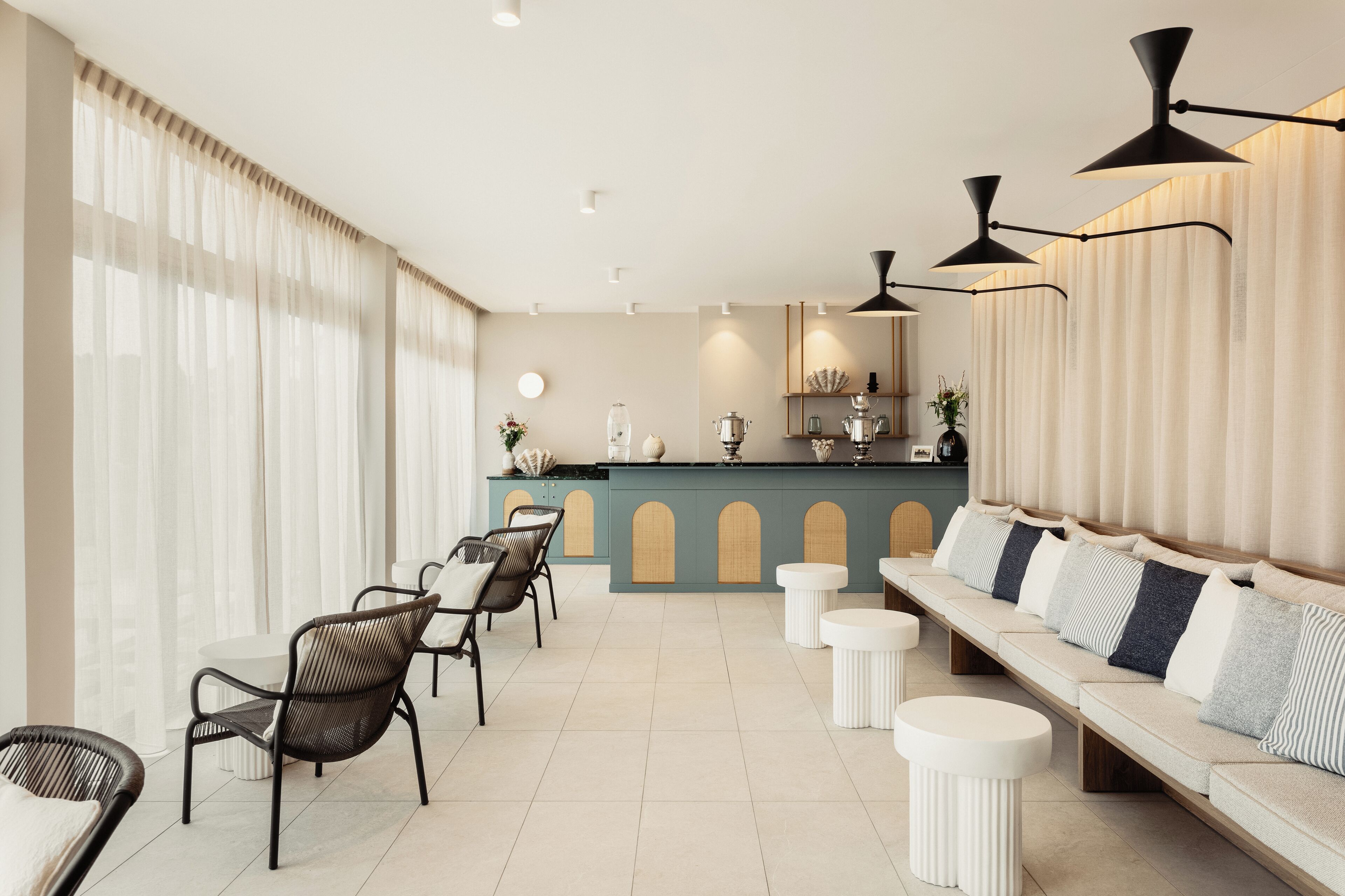 Un espace de détente moderne comprenant un canapé, des fauteuils, une petite table et un coin bar agrémenté d’objets décoratifs.