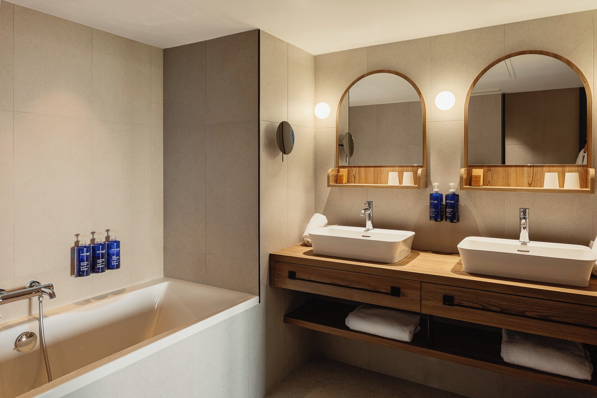 Un baño moderno con bañera, dos lavamanos y un tocador con espejo.
