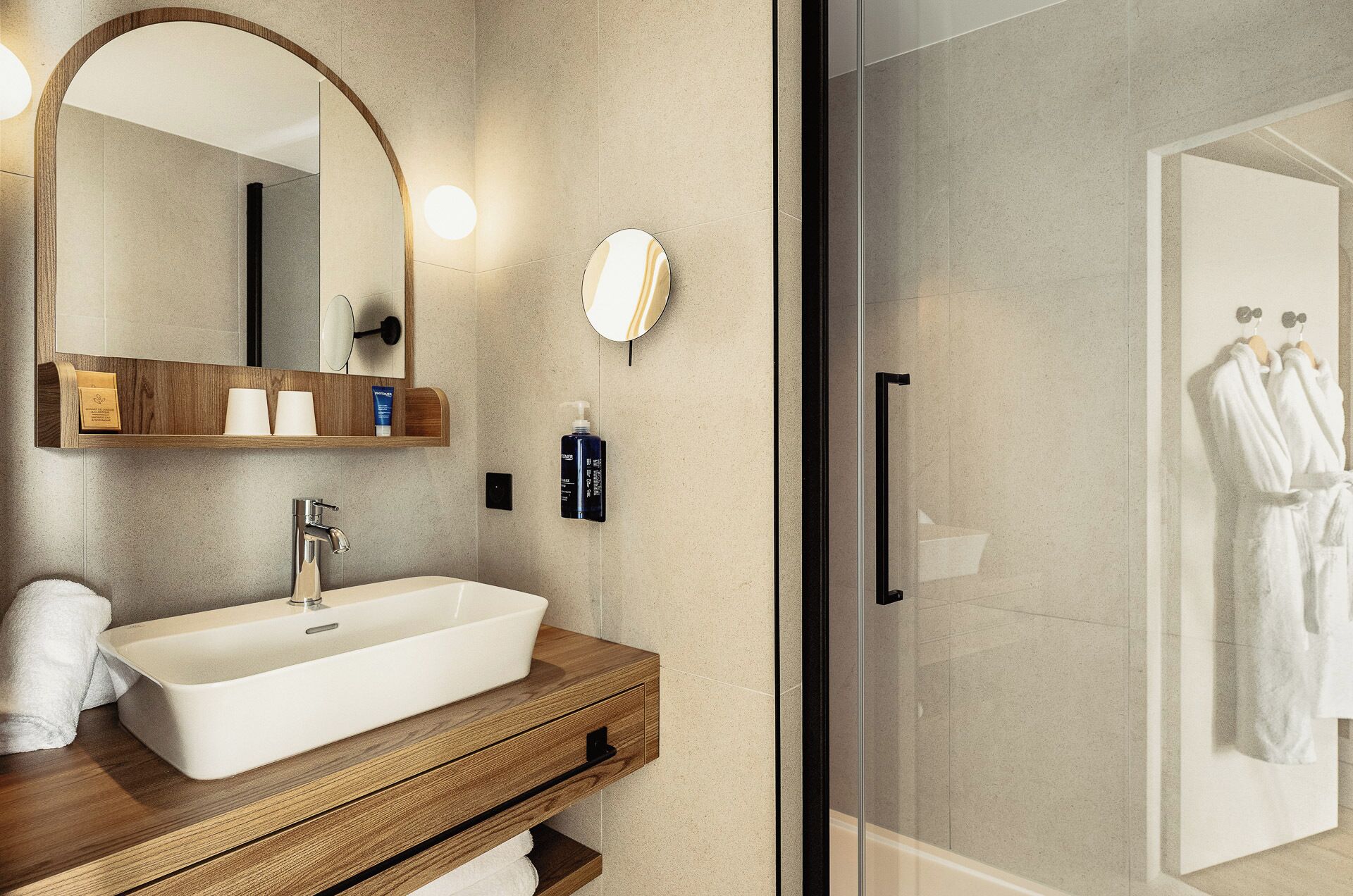 A modern bathroom with a large mirror, a wooden vanity, a white sink, and a glass shower enclosure.