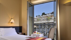 A hotel room with a bed, a nightstand, a table with breakfast, and a balcony with a view of buildings. - Best Western Hotel Metropoli (Genoa)