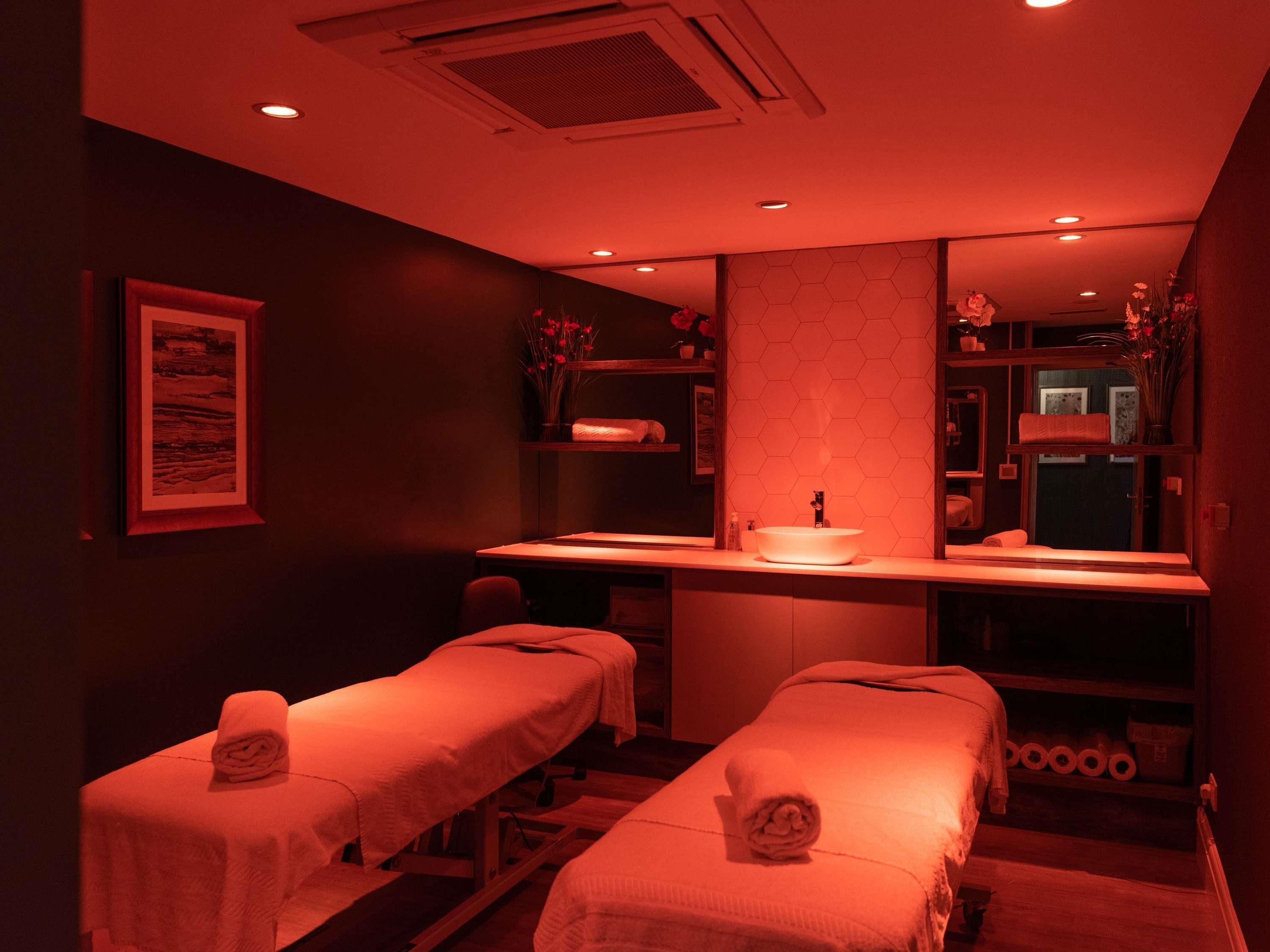 Una sala spa con due lettini per trattamenti, un lavandino e uno specchio.