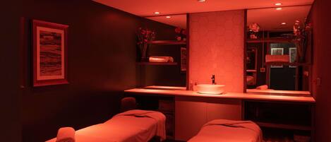 Una sala spa con due lettini per trattamenti, un lavandino e uno specchio.