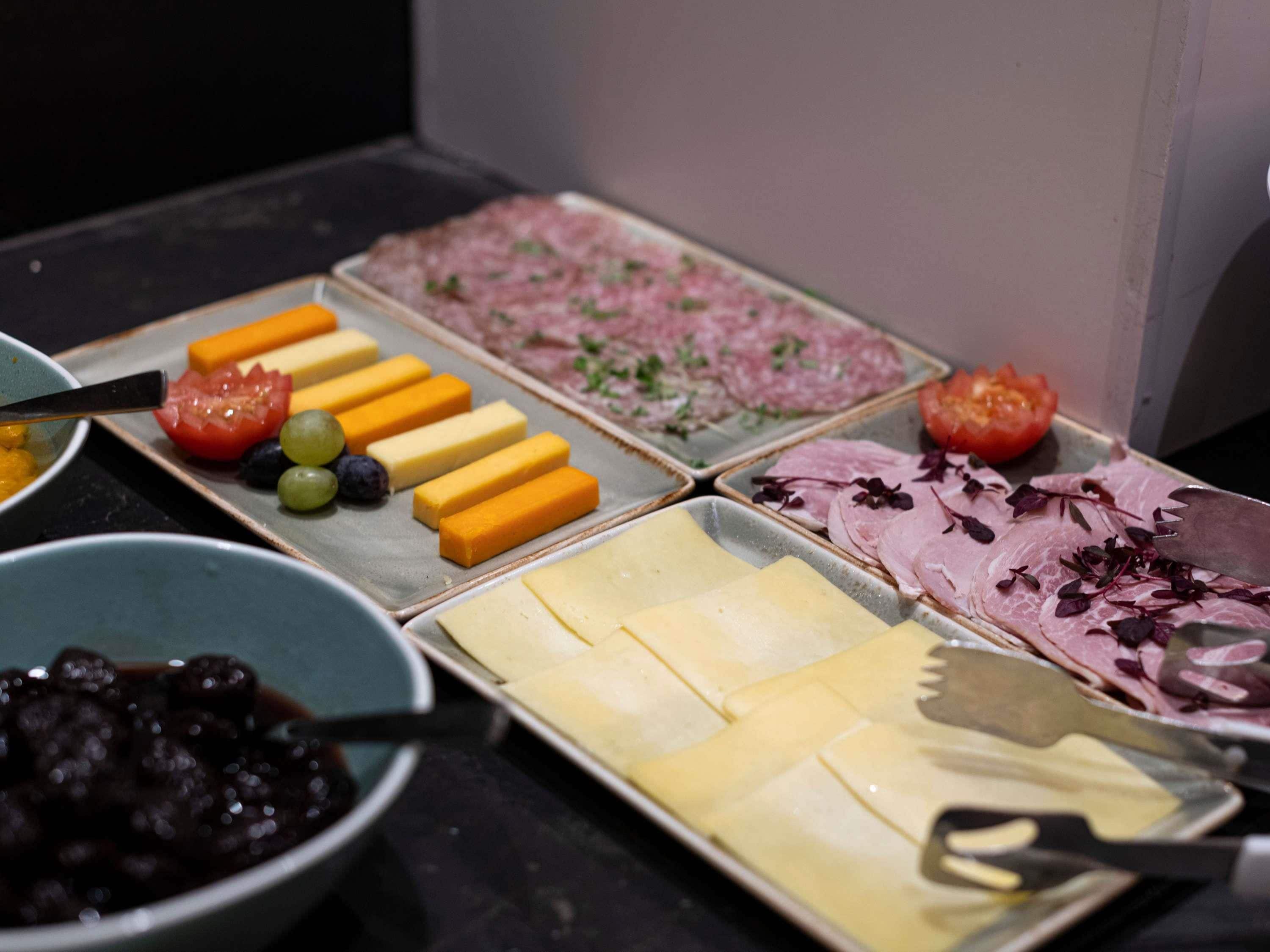 Un buffet proposant une variété d’aliments, notamment des fromages, des viandes et des fruits.