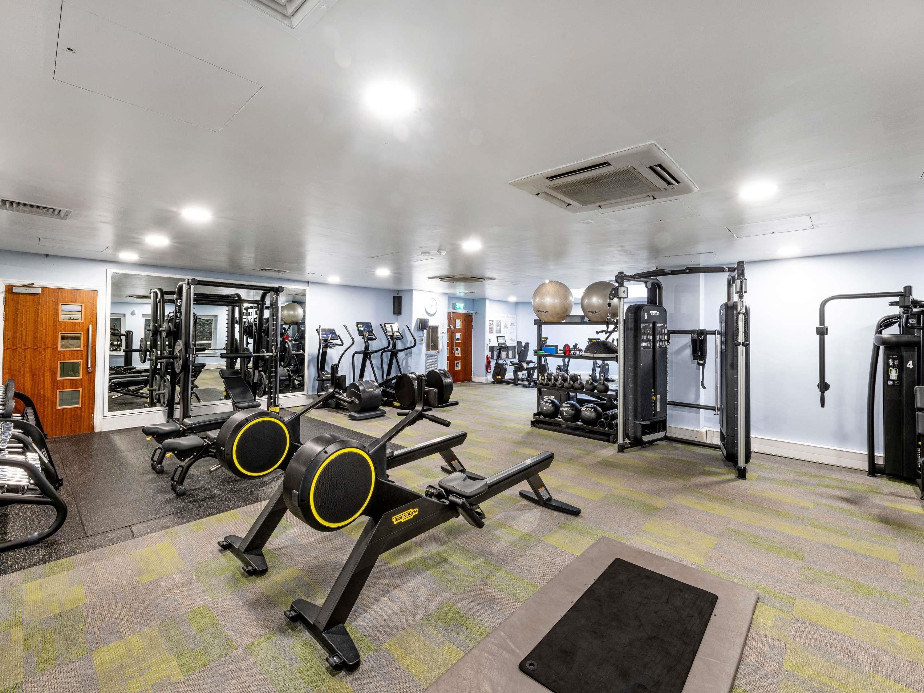 A gym with exercise equipment, a mirror, and a patterned carpet.