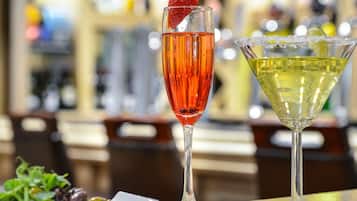 Two cocktails on a bar counter with a blurred background.