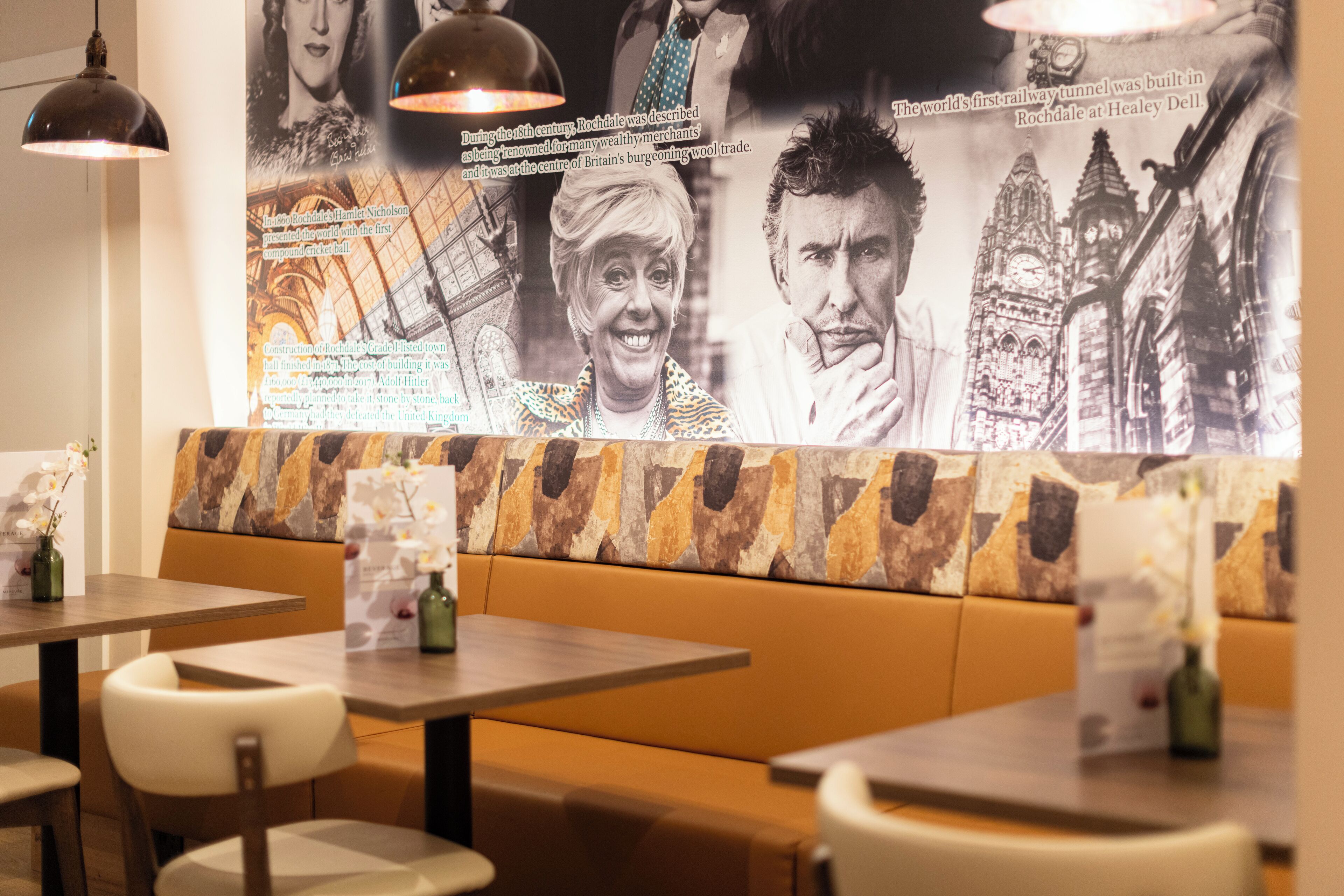 Un interior de restaurante con cabinas, mesas y un póster histórico grande en la pared.