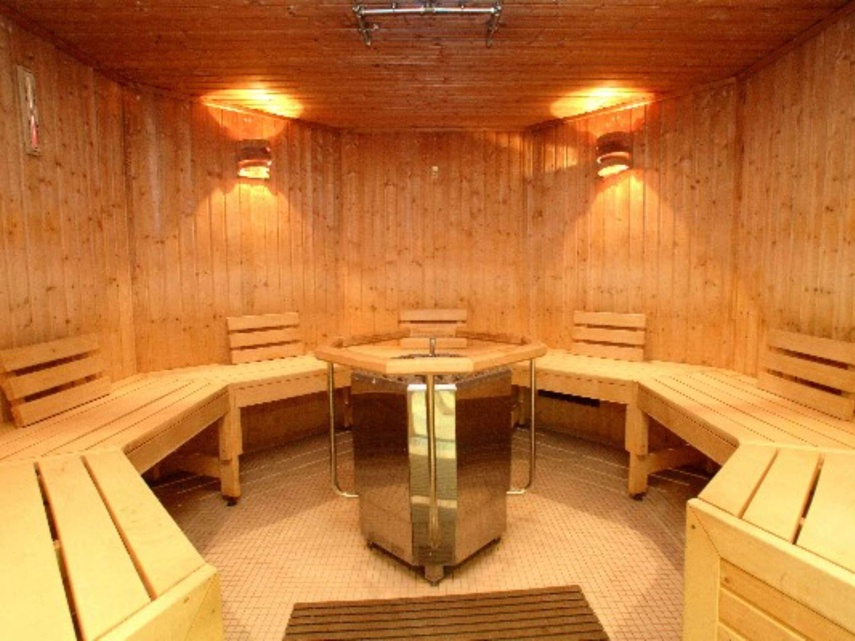 A sauna room with wooden benches and a central table.