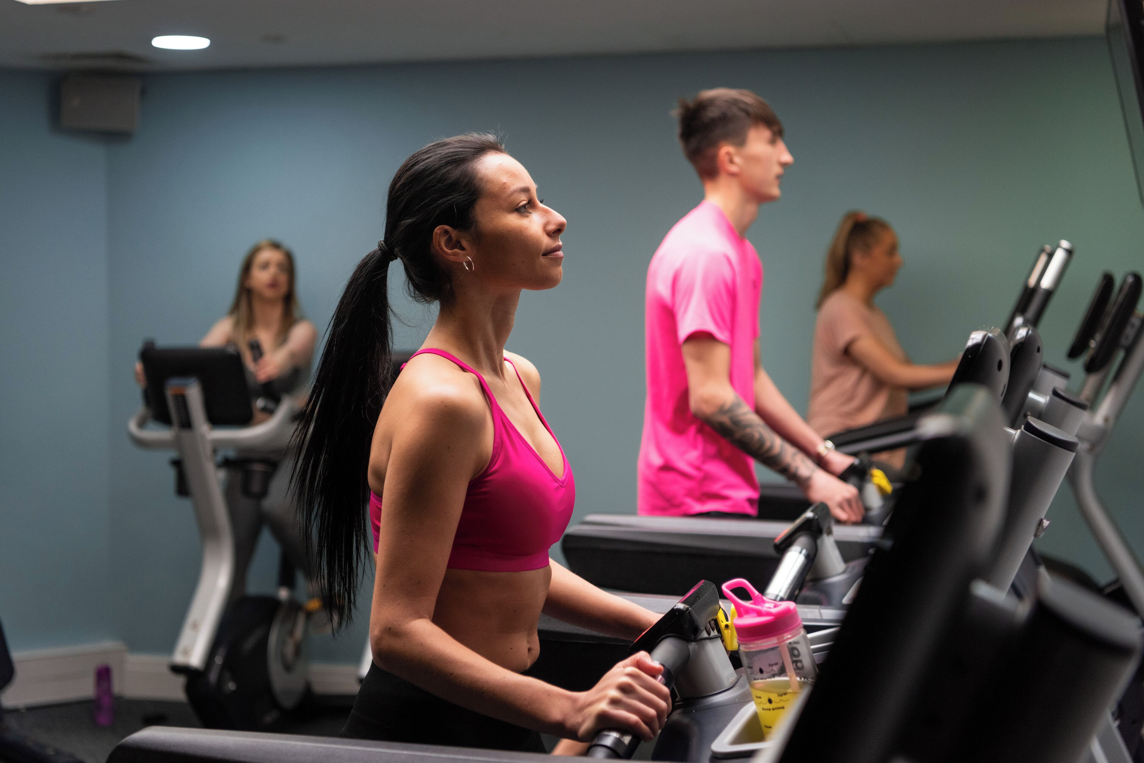 A gym with treadmills and stationary bikes, a mirror on the wall, and a blue wall.