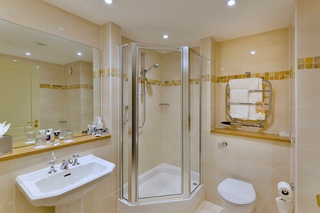 A bathroom with a glass-enclosed shower, a sink, a toilet, and a towel rack.