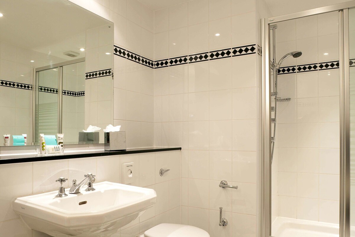 Un baño moderno con un lavamanos blanco, un inodoro y una ducha con mampara de vidrio.