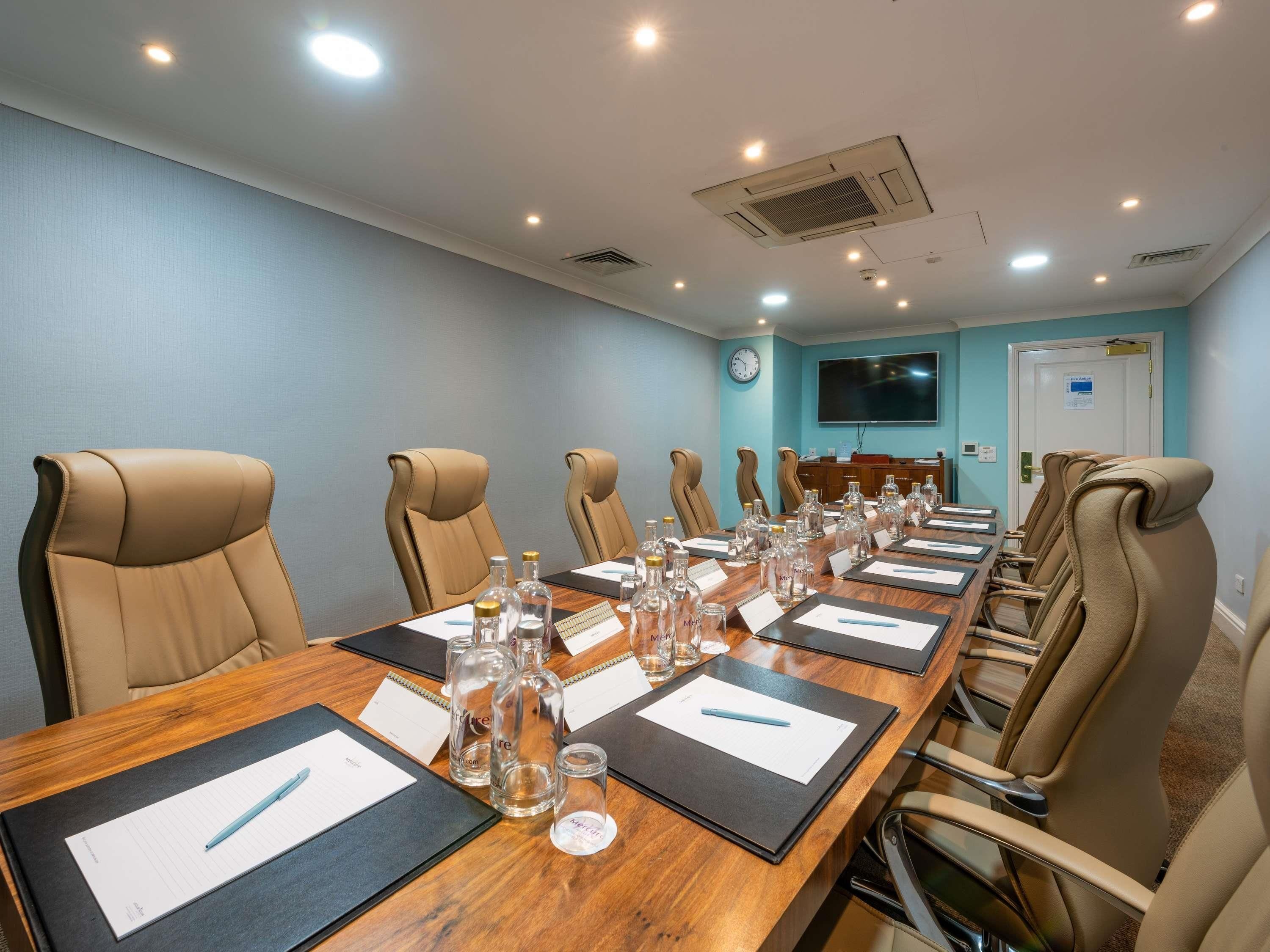 A conference room with a long table, multiple chairs, and a television on the wall.