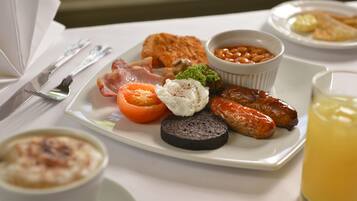 Un plato de desayuno con huevos, tocino, salchichas, tomates y frijoles.