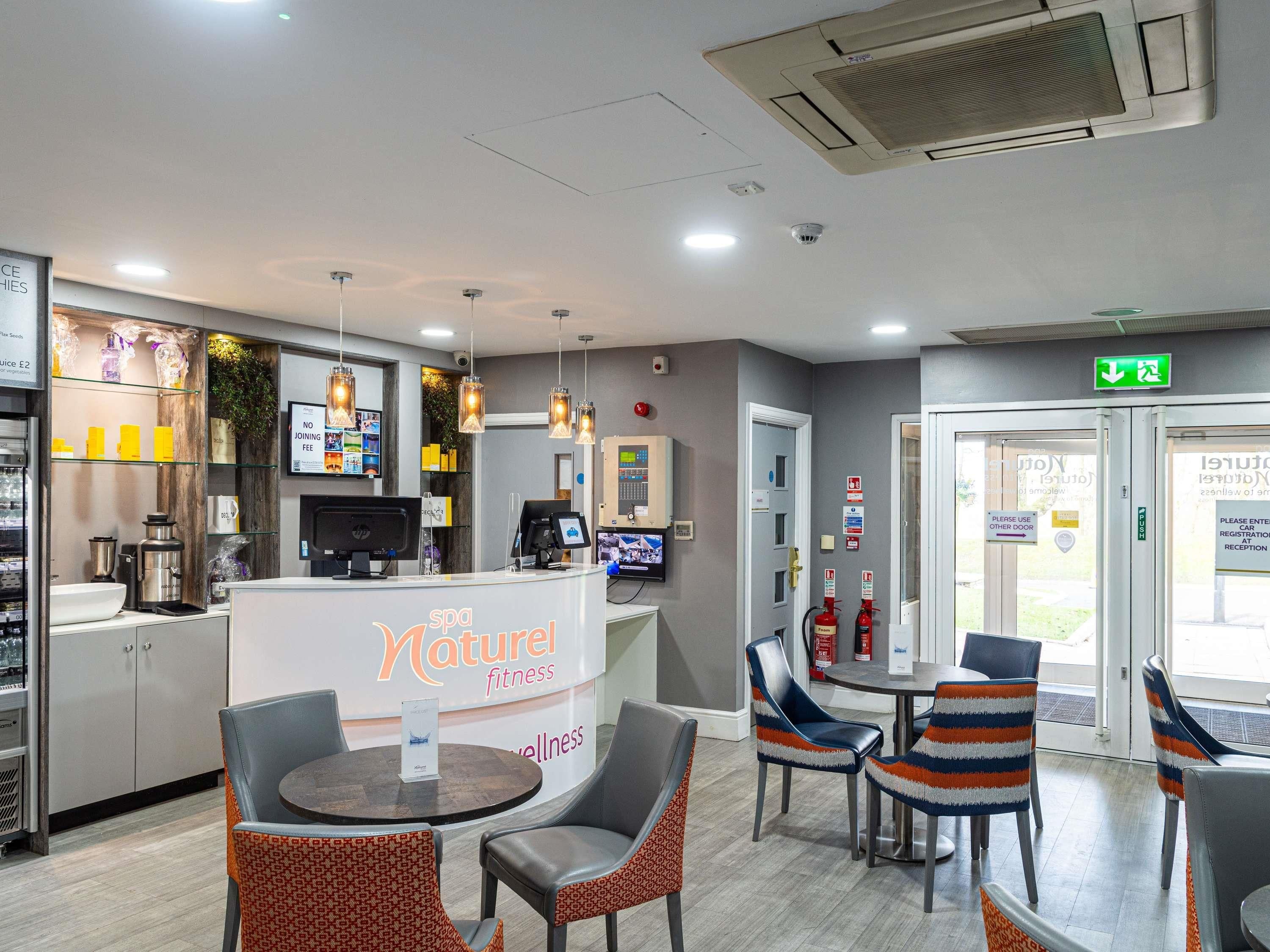 A reception area with a counter, seating, and a sign for 'spa Naturer fitness wellness'.