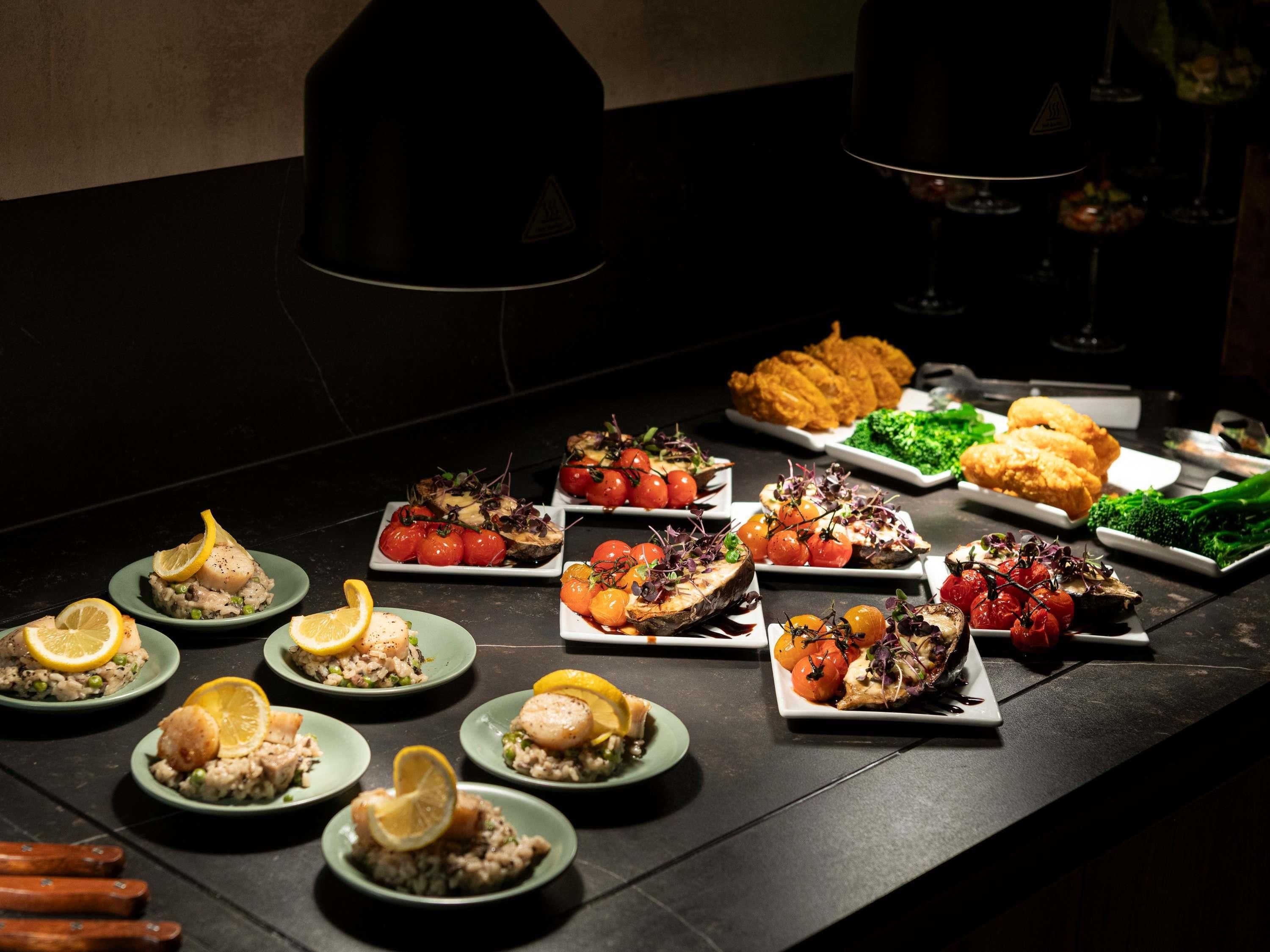 A buffet table with various dishes, including seafood, vegetables, and bread.