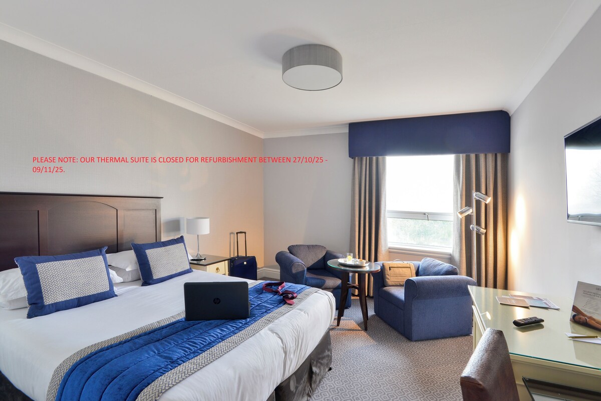 Una habitación de hotel con una cama, un escritorio, una silla y una mesita.