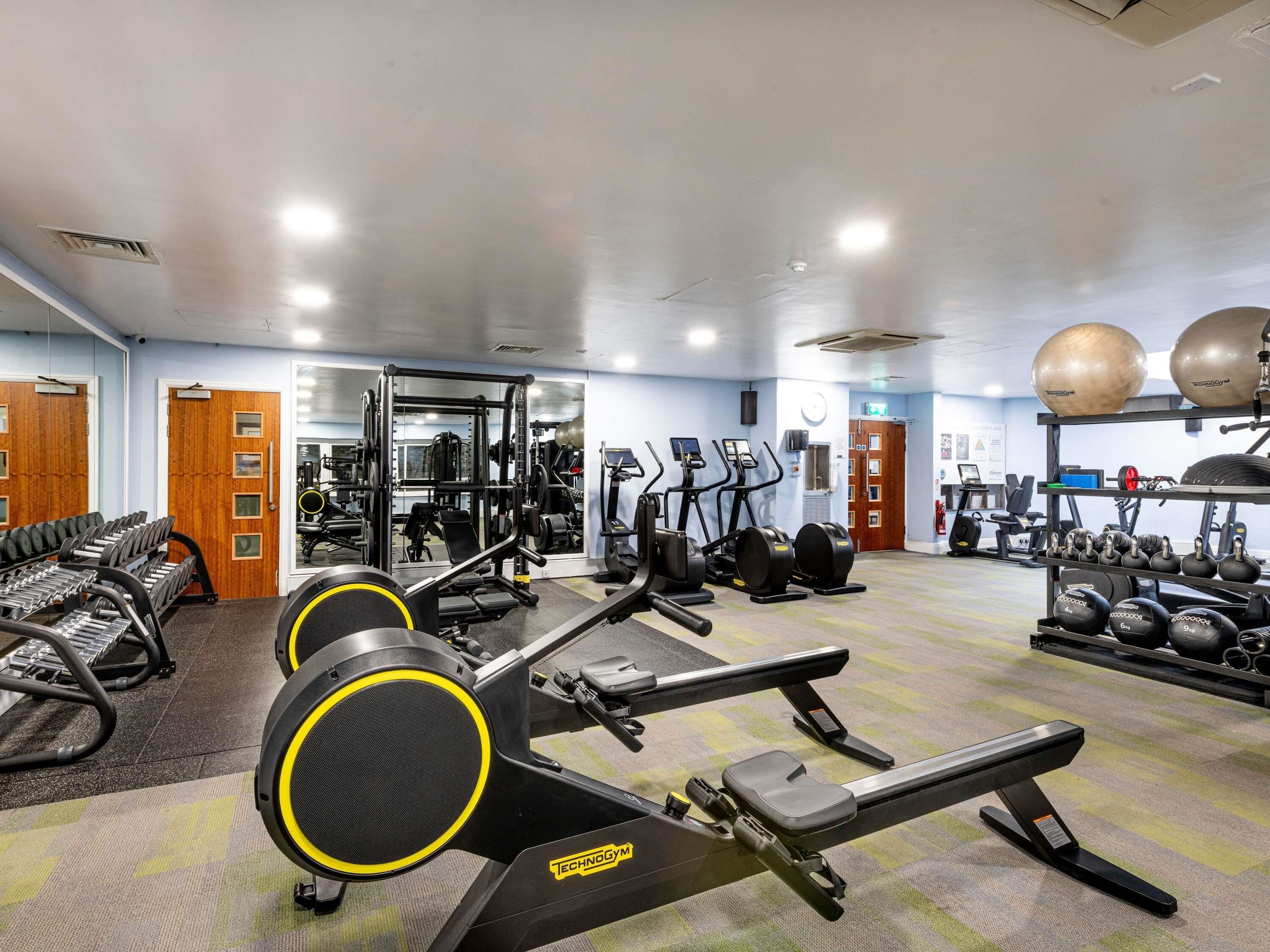 A gym with exercise equipment, weight racks, and a mirrored wall.