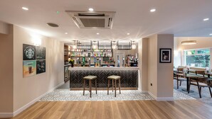 Un espace bar avec des tabourets, un comptoir où sont exposées différentes bouteilles et un sol à motifs.