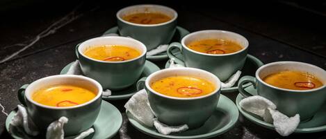 A table with six bowls of soup on matching green saucers.
