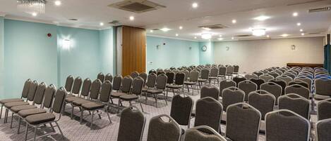 A conference room with rows of chairs, a clock, and a wooden door.