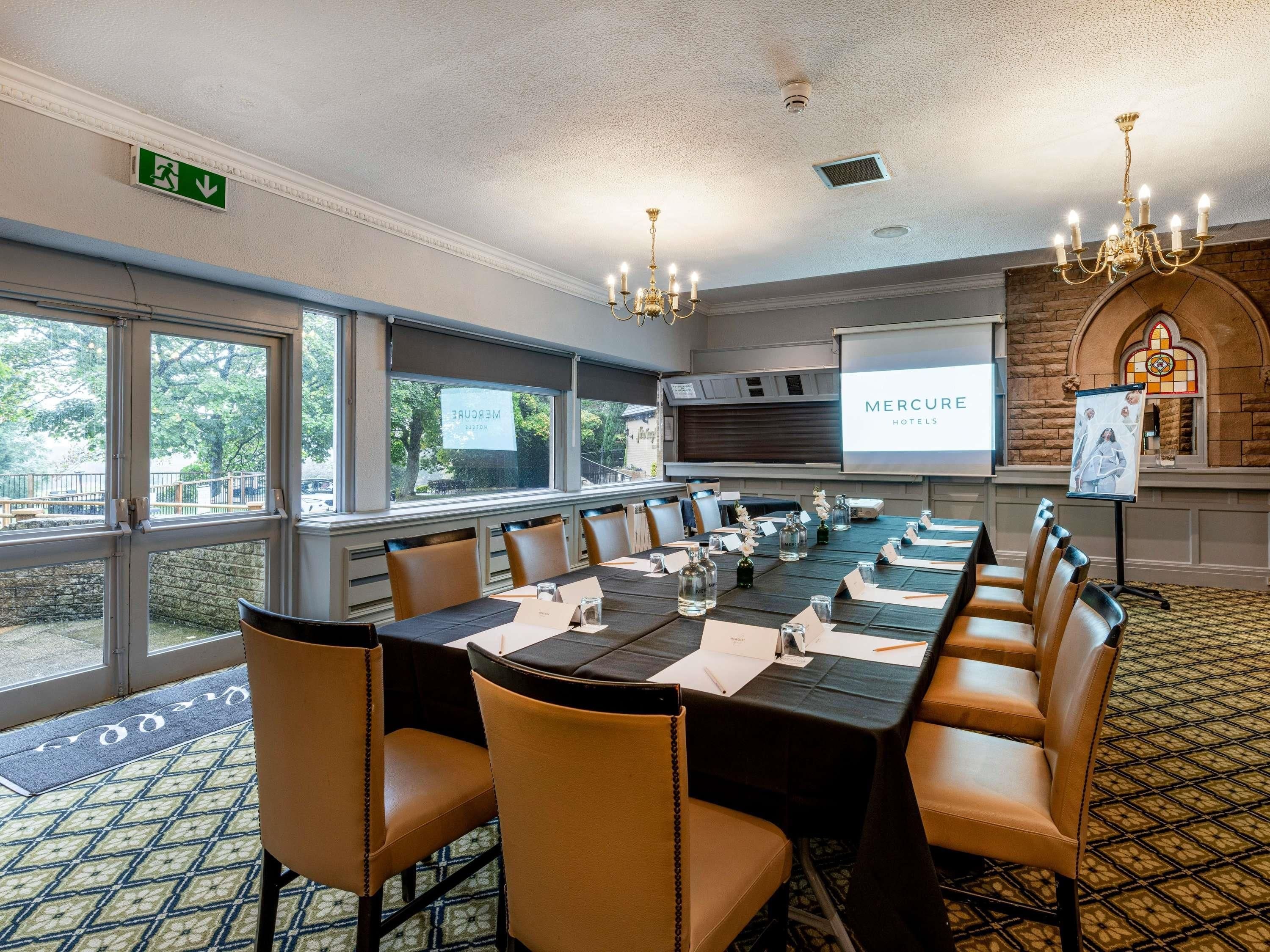 A conference room with a long table, chairs, a projector screen, and a fireplace.