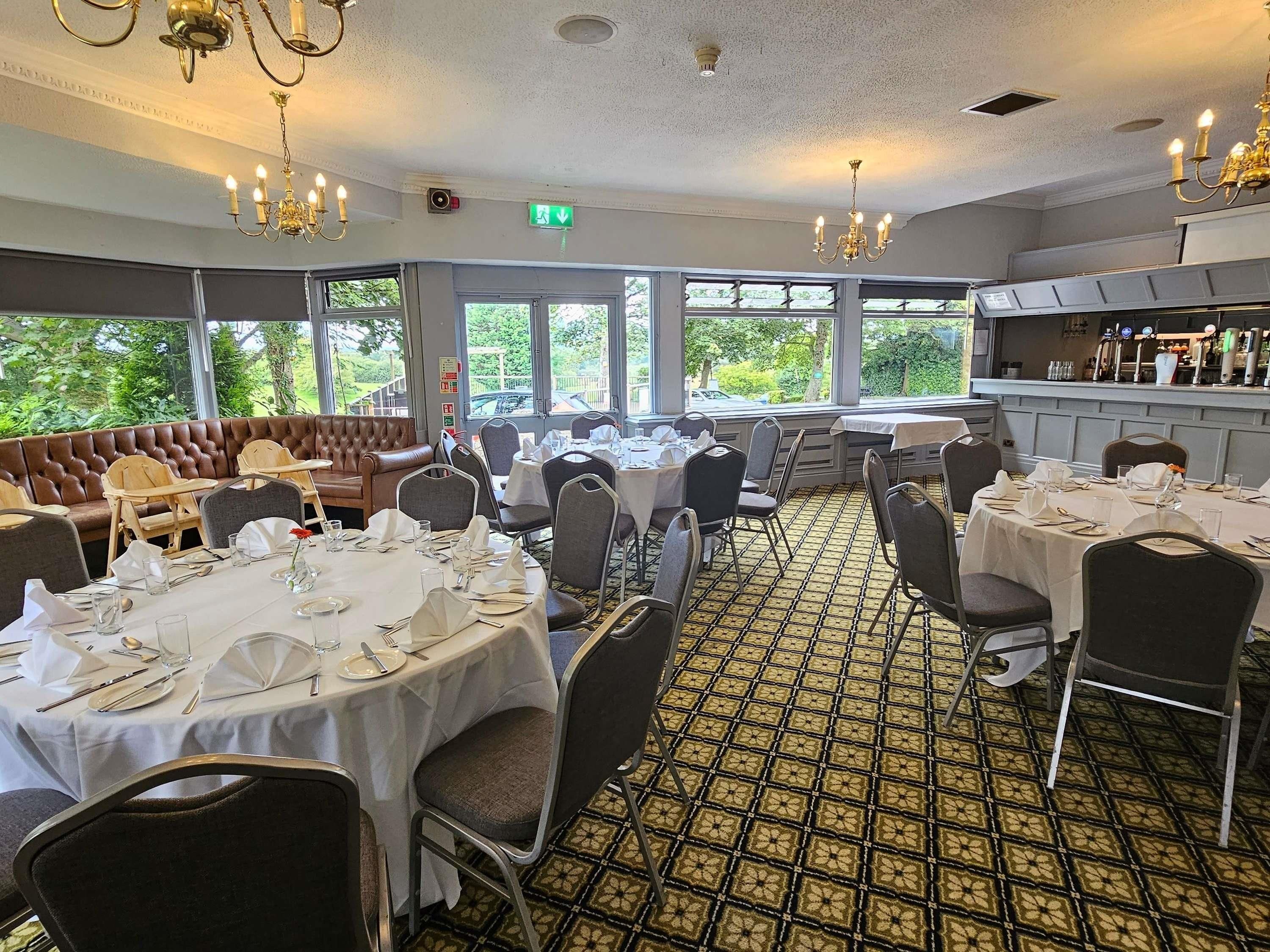 A restaurant with round tables, chairs, and a booth seating area.